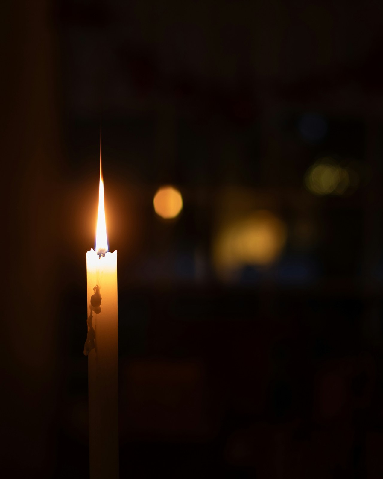 A single lit candle glowing in a dim room